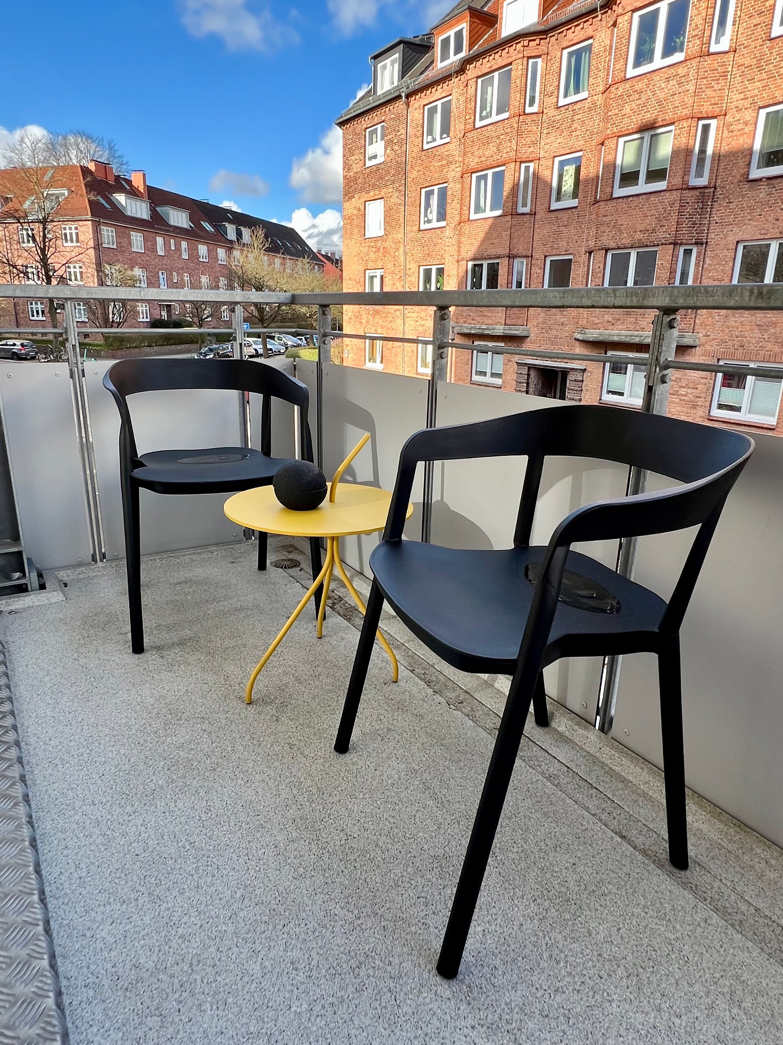 Balkon mit zwei Stühlen und einem kleinen Tisch, Blick in die Bülowstraße.