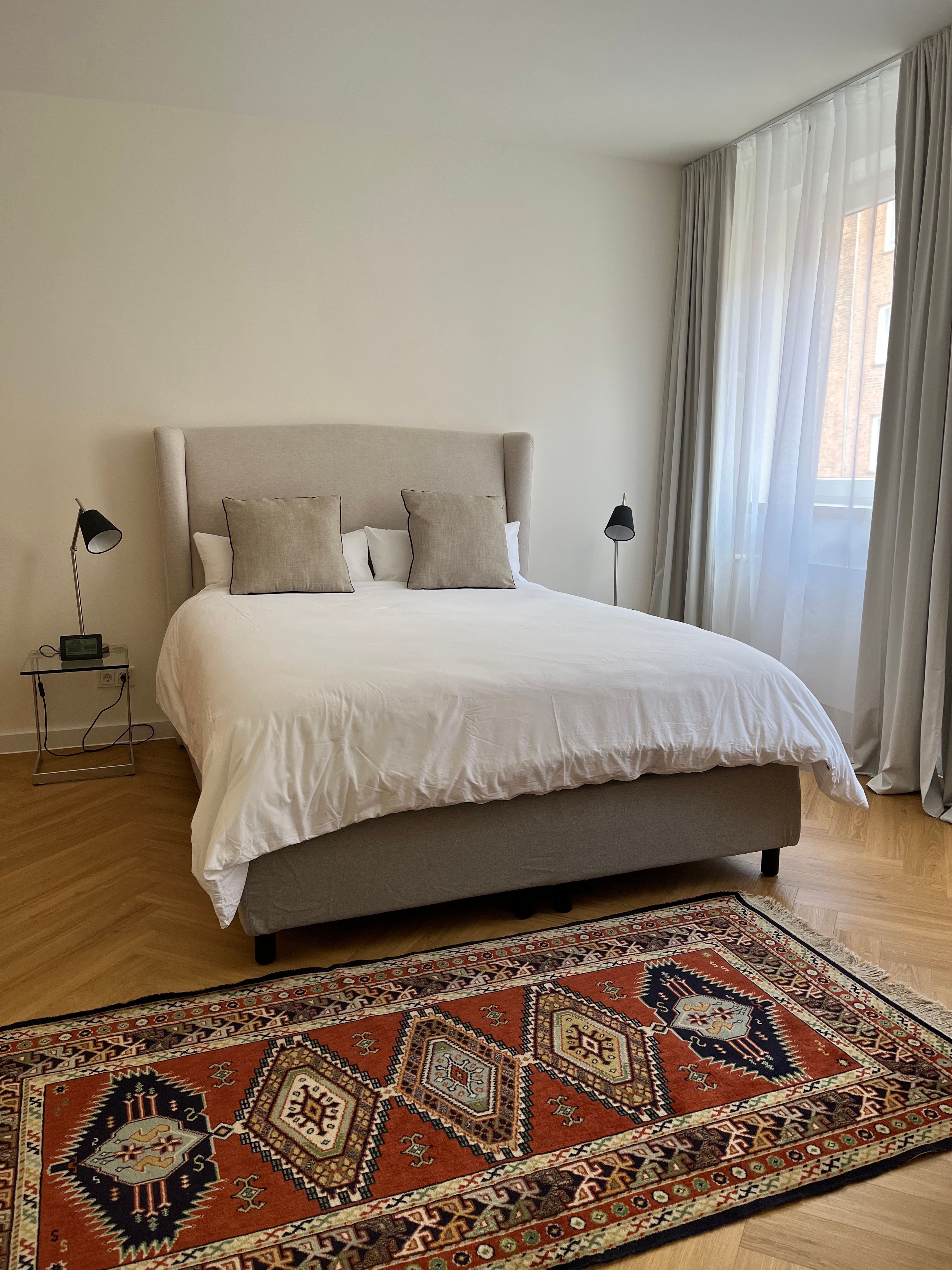 Schlafzimmer mit Boxspringbett, Nachttischen und Leselampen auf beiden Seiten.